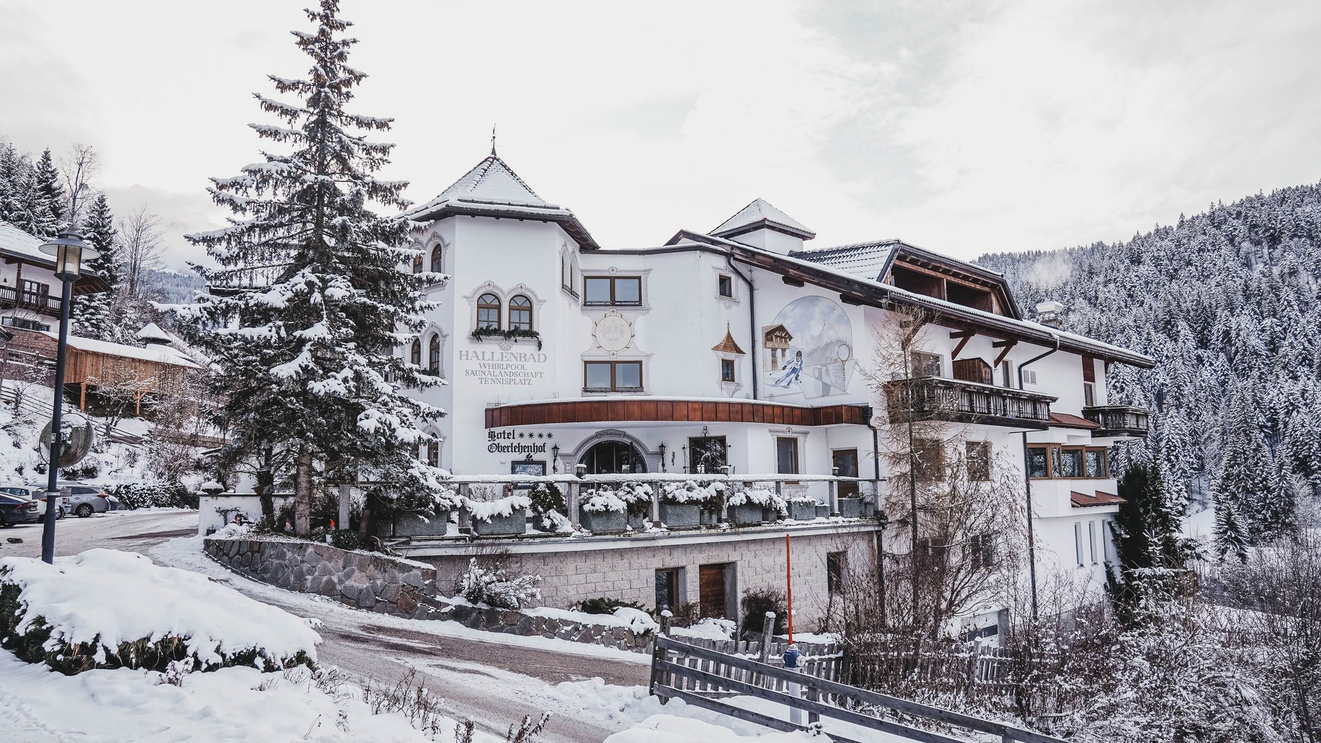 Sentitevi come a casa nel nostro hotel vicino a Obereggen! Hotel innevato in montagna con alberi di pino coperti di neve