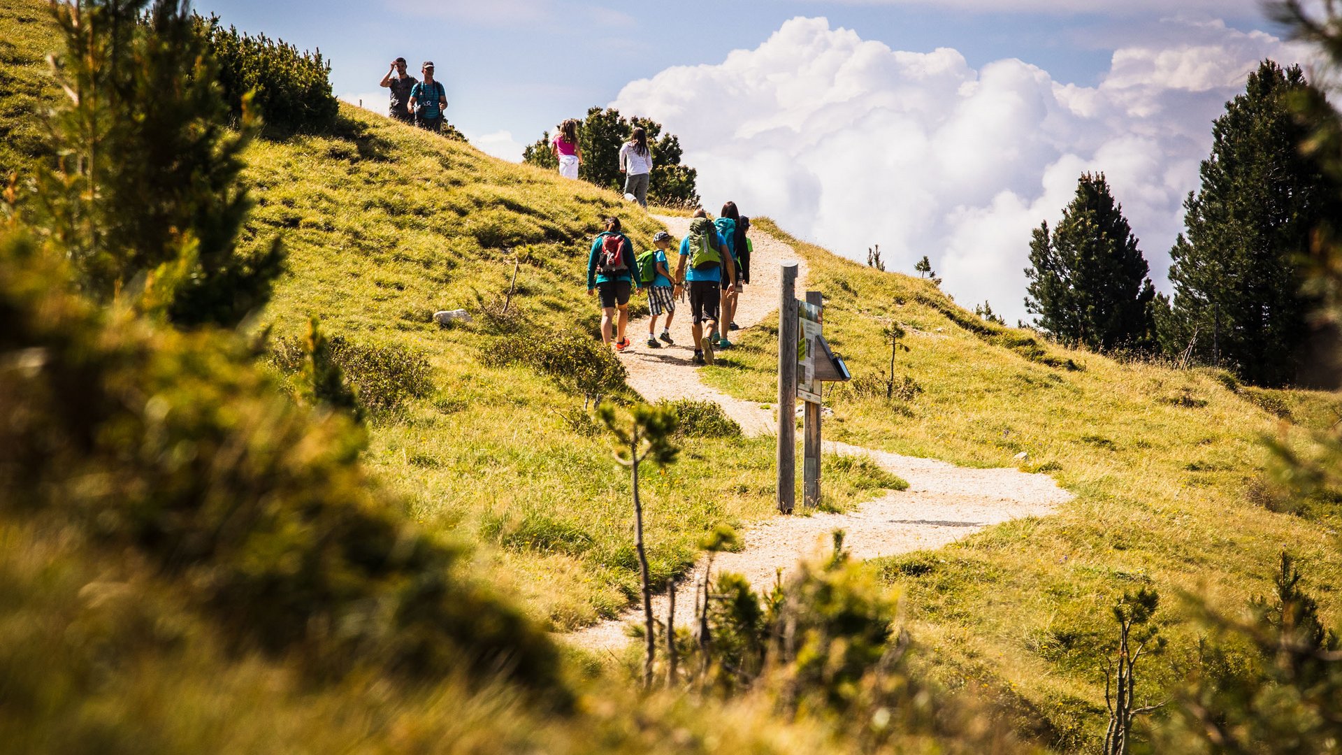 Familiengeführtes Aktivhotel in Südtirol: der Oberlehenhof Wanderer auf einem Bergweg bei sonnigem Wetter mit bewölktem Himmel