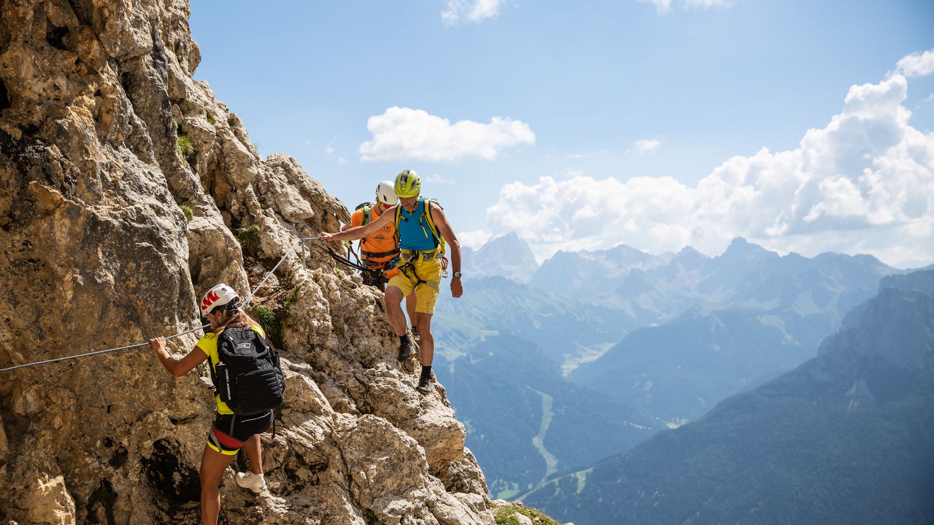Vacanze in Val d’Ega = Esperienze uniche Tre alpinisti su sentiero roccioso con sicurezza a corda sulle Alpi