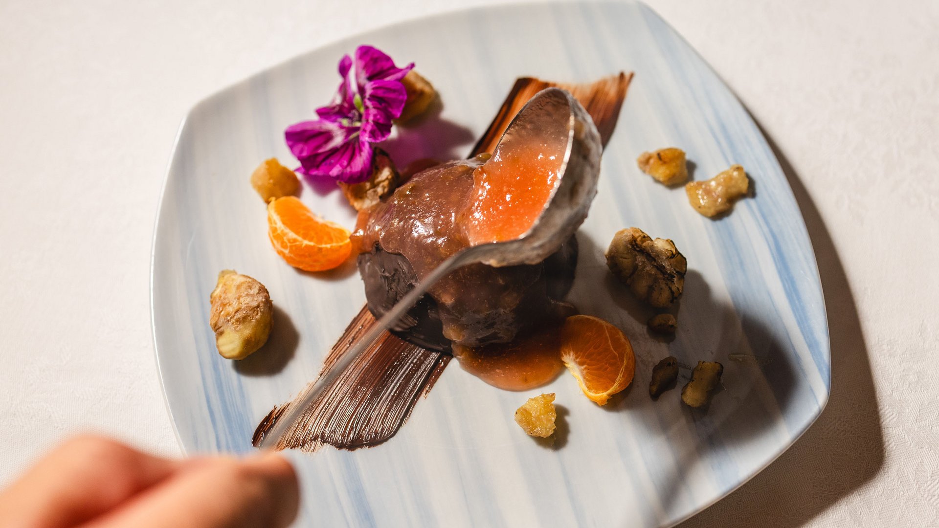 Hotel con mezza pensione tra le Dolomiti: Oberlehenhof Dessert al cioccolato con salsa d'arancia, noci e fiore su un piatto