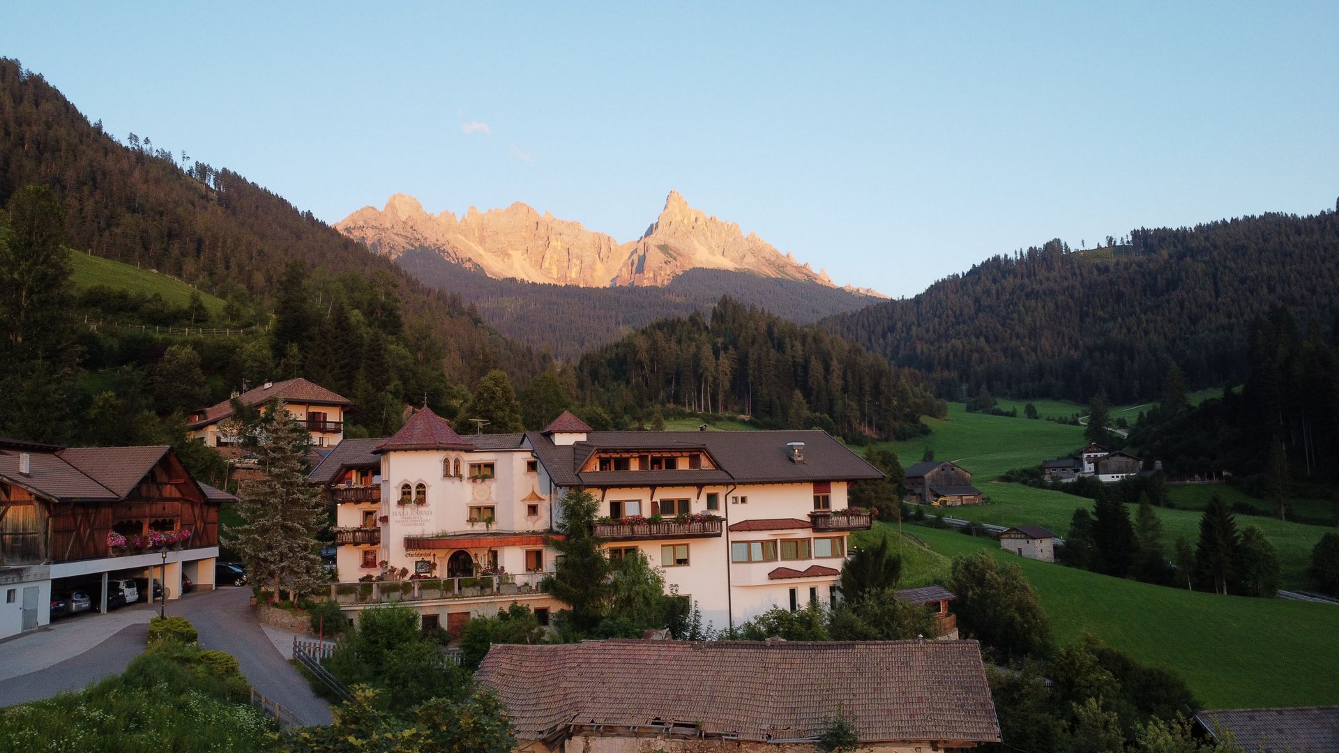 Hotel antico in una valle con montagne e boschi al tramonto